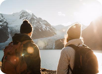 Hikers watching Mount Cook with snow-capped peaks and alpine lake